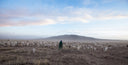 Herder in a green deel walking with a large herd of goats and sheep across the dry Mongolian steppe
