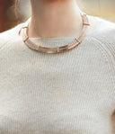 Close-up of ribbed light gray cashmere sweater neckline worn with a metal collar necklace, showing Mongolian cashmere quality