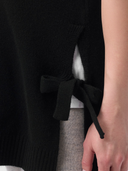 Close-up of a person wearing a black top with a tie detail.