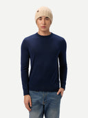 Man wearing a navy sweater, beige beanie, and jeans on a white background.