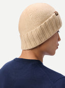 back view of a person wearing a beige knit beanie on a white background