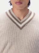 Close-up of a person wearing a ribbed knit V-neck sweater with a striped v-neck collar in beige, cream, and taupe.