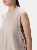 Close-up side view of a model wearing a sleeveless knit vest in a light oatmeal beige color, featuring a crew neck and side buttons.