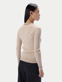 A woman shown from the back wearing a beige ribbed knit sweater with thin red and white striped trim at the collar and cuffs, paired with black pants, against a light gray studio background.
