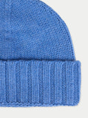 close up of a blue knit beanie on a light gray background
