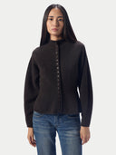 A woman modeling a dark brown mock-neck button-up cardigan sweater with long sleeves, paired with blue jeans, against a light gray studio background.