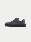 A pair of low-top sneakers in dark gray and black, featuring a textured fabric upper, matching gray laces, and black soles, photographed on a light gray studio background. #color_cool-stone