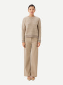 A woman wearing a beige and brown striped sweater with round neckline. #color_soft-white