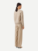 A woman wearing a beige and brown striped sweater with round neckline. #color_soft-white