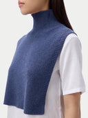 Person wearing a blue knitted vest over a white shirt on a light gray background. #color_soft-indigo
