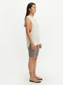 A woman wearing a sleeveless beige knitted top with a round neckline . #color_white