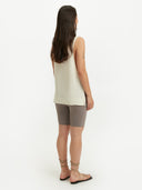 A woman wearing a sleeveless beige knitted top with a round neckline . #color_white