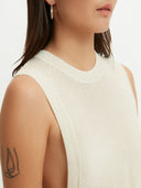 A woman wearing a sleeveless beige knitted top with a round neckline . #color_white
