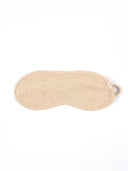 A light beige textured knit sleep mask with a small matching fabric loop on the side, shown flat against a solid white background.