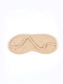 A light beige textured knit sleep mask with a small matching fabric loop on the side, shown flat against a solid white background.