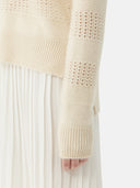A woman wearing a beige organic color mixed pattern cashmere polo neck sweater with a V-neckline and long sleeves. #color_off-white