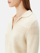 A woman wearing a beige organic color mixed pattern cashmere polo neck sweater with a V-neckline and long sleeves. #color_off-white