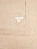 Close-up of a soft knit fabric in a light warm beige tone, showing a small white woven brand tag that reads GOBI