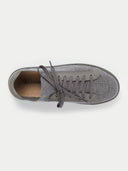 A pair of low-top sneakers in dark gray and black, featuring a textured fabric upper, matching gray laces, and black soles, photographed on a light gray studio background. #color_cool-stone