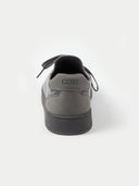 A pair of low-top sneakers in dark gray and black, featuring a textured fabric upper, matching gray laces, and black soles, photographed on a light gray studio background. #color_cool-stone