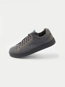 A pair of low-top sneakers in dark gray and black, featuring a textured fabric upper, matching gray laces, and black soles, photographed on a light gray studio background. #color_cool-stone