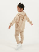 Child wearing a beige cashmere tracksuit on a white background #color_beige