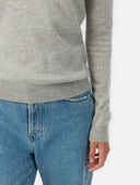 Person wearing a gray cashmere sweater and light blue jeans on a white background. #color_steel-silver