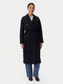 Full-length front view of black belted long coat styled with blue jeans and heeled boots