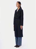 Side view of the black double-breasted coat worn open over jeans, showing midi length
