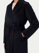 Detail of black buttons, wide lapel, tied belt and side pocket with hand inserted