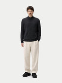 Man wearing a black zip-up cashmere sweater and beige pants on a white background. #color_charcoal