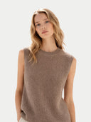 Woman wearing a brown sleeveless knitted sweater against a light background. #color_taupe