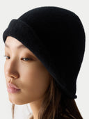 Woman wearing a black knit beanie against a white background