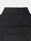 Close-up of a black puffer vest with a brand logo on a light gray background