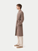 Man wearing a brown robe standing against a white background