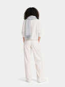 back view of a person wearing a light gray sweater and white pants on a white background
