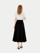 back view of a woman wearing a white top and black skirt on a white background