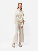 A pair of beige, organic cashmere wide-leg pants with a high waist and ankle-length cut, paired with a white top and beige shoes. #color_off-white