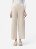 A pair of beige, organic cashmere wide-leg pants with a high waist and ankle-length cut, paired with a white top and beige shoes. #color_off-white