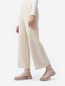 A pair of beige, organic cashmere wide-leg pants with a high waist and ankle-length cut, paired with a white top and beige shoes. #color_off-white