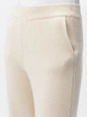 A pair of beige, organic cashmere wide-leg pants with a high waist and ankle-length cut, paired with a white top and beige shoes. #color_off-white
