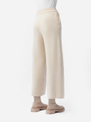 A pair of beige, organic cashmere wide-leg pants with a high waist and ankle-length cut, paired with a white top and beige shoes. #color_off-white