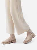 A pair of beige, organic cashmere wide-leg pants with a high waist and ankle-length cut, paired with a white top and beige shoes. #color_off-white