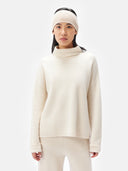 A model is wearing beige cashmere ribbed knit headband with a small white rectangular brand tag, displayed flat against a light gray background. #color_beige