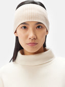 A model is wearing beige cashmere ribbed knit headband with a small white rectangular brand tag, displayed flat against a light gray background. #color_beige