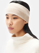 A model is wearing beige cashmere ribbed knit headband with a small white rectangular brand tag, displayed flat against a light gray background. #color_beige