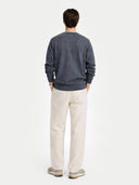 Man wearing a dark gray sweater and beige pants on a white background