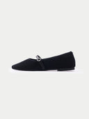 Pair of black flat shoes with a strap on a light gray background #color_black
