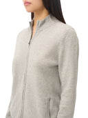 A close-up side view of a woman wearing a light heather gray zip-up jacket against a plain white background.