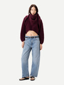 Women wearing a burgundy cashmere sweater and light blue jeans on a white background